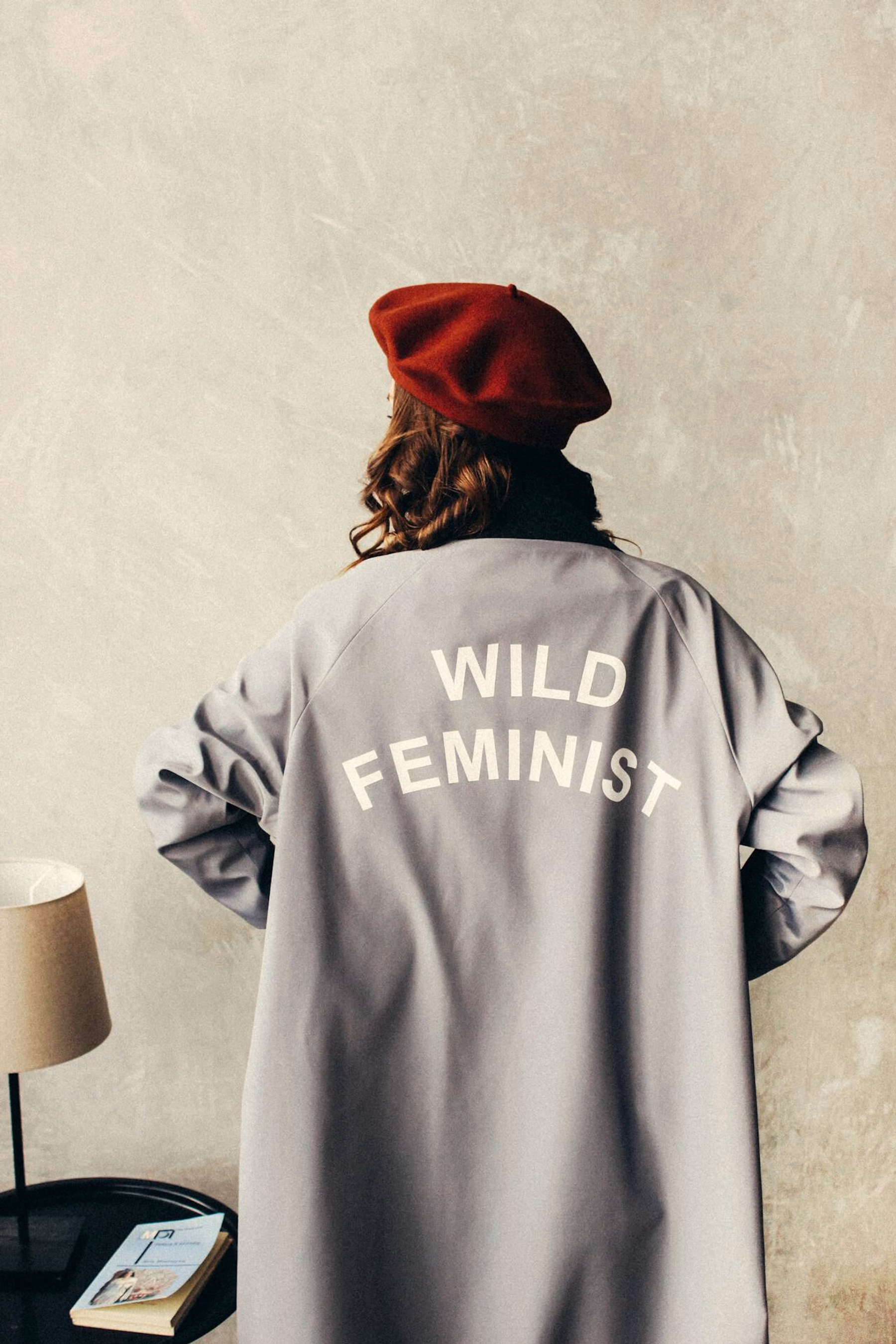 Eine Frau von hinten fotografiert mit einem Mantel an auf dem geschrieben steht "Wild Feminist"