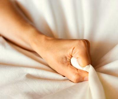 Eine Frau die Lustvoll ins Bettlaken greift