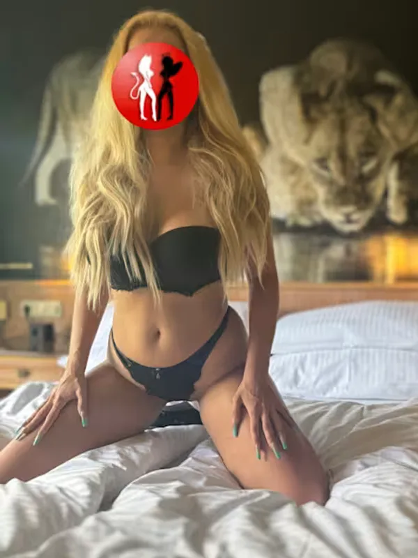 Escort Sophia aus Leipzig kniet auf dem Bett und trägt ein schwarzes Dessous-Set, das ihre Brüste und Hüften sexy in Szene setzt. Ihre langen blonden Haare fallen über die Schultern, während sie sich verführerisch präsentiert. Der Blick auf ihren Körper verspricht pure Lust und hemmungslosen Spaß.