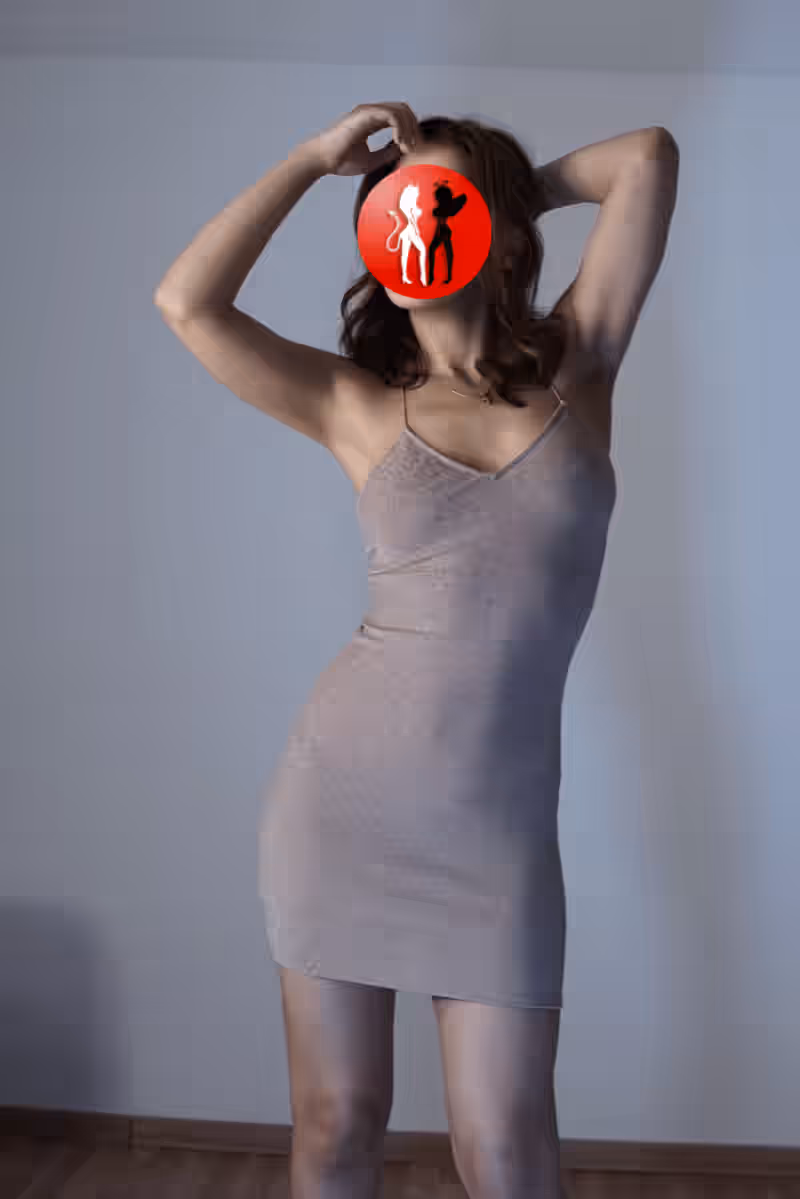 In einem schimmernden, nudefarbenen Minikleid mit Spaghettiträgern posiert Valeria mit erhobenen Armen und geschwungenem Rücken. Die Lichtführung erzeugt sanfte Schatten und hebt die feminine Linienführung des Kleides hervor. Der Gesamteindruck ist modern, selbstsicher und sinnlich-zurückhaltend.

