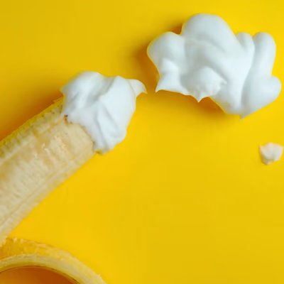 Eine Banane und Sahne, zusammen fotografiert sieht es aus wie ein Spermafleck